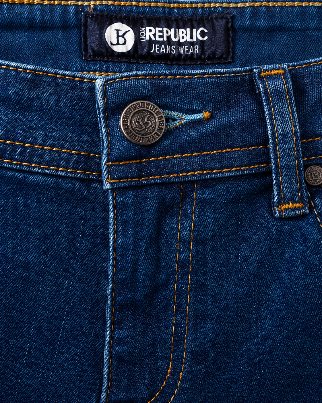 Détail ceinture bouton métal jean bleu indigo surpiqûres oranges — Zalimi